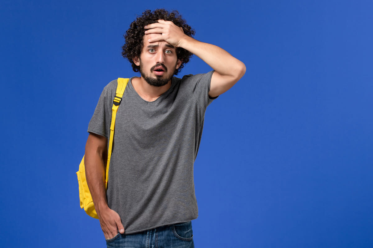 front-view-young-male-grey-t-shirt-wearing-yellow-backpack-posing-with-confused-expression-blue-wall